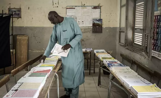 A man collects voting cards, that are set on a table, before casting his vote for legislative elections at a polling station in Dakar, Senegal Sunday, Nov. 17, 2024. (AP Photo/Annika Hammerschlag)