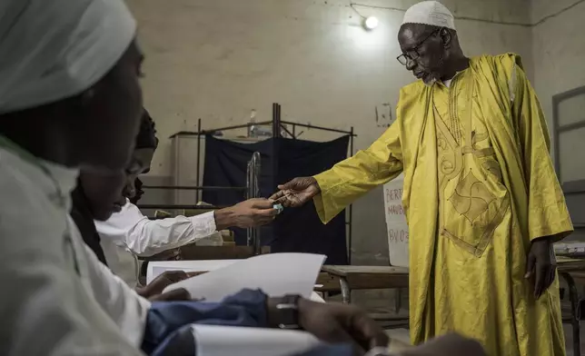 A man has his identity verified before casting his vote during legislative elections in Dakar, Senegal Sunday, Nov. 17, 2024. (AP Photo/Annika Hammerschlag)