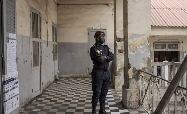 A member of security forces stands guard as people wait to cast their votes outside a polling station during the legislative elections in Dakar, Senegal Sunday, Nov. 17, 2024. (AP Photo/Annika Hammerschlag)