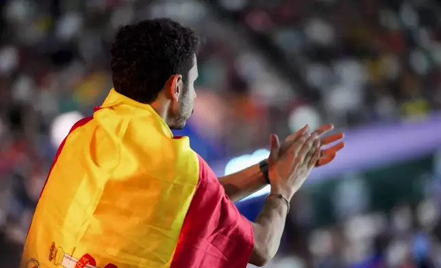 A spectator wrapped with the Spanish flag applauds during the match between Spain's tennis player Rafael Nadal and Netherlands' Botic Van De Zandschulp during a Davis Cup quarterfinal match at Martin Carpena Sports Hall in Malaga, southern Spain, on Tuesday, Nov. 19, 2024. (AP Photo/Manu Fernandez)