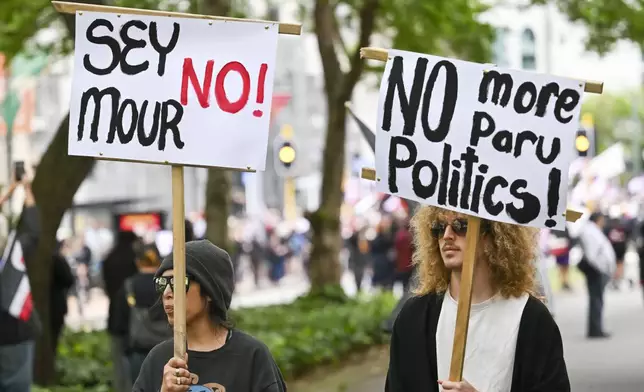 Protesters march carrying placards to New Zealand's parliament to demonstrate against a proposed law that would redefine the country's founding agreement between Indigenous Māori and the British Crown, in Wellington, New Zealand, Tuesday, Nov. 19, 2024. (AP Photo/Mark Tantrum)