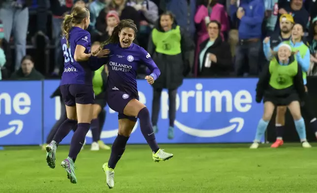 Orlando Pride midfielder Angelina, center, celebrates her assist on a goal by Pride forward Barbra Banda with teammate Pride defender Cori Dyke (31) during the first half of the NWSL championship at CPKC Stadium against the Washington Spirit, Saturday, November 23, 2024, in Kansas City, Mo. (AP Photo/Reed Hoffmann)