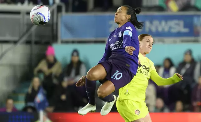 Orlando Pride forward Marta (10) leaps into the air to make a play on a ball in front of Washington Spirit midfielder Hal Hershfelt, right, during the first half of the NWSL championship at CPKC Stadium, Saturday, Nov. 23, 2024, in Kansas City, Mo. (AP Photo/Reed Hoffmann)