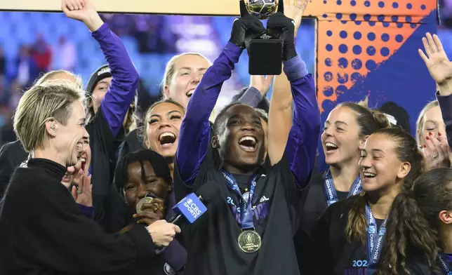 Orlando Pride forward Barbra Banda, center, raises her MVP trophy after the team defeated the Washington Spirit in the NWSL championship soccer game at CPKC Stadium, Saturday, Nov. 23, 2024, in Kansas City, Mo. (AP Photo/Reed Hoffmann)