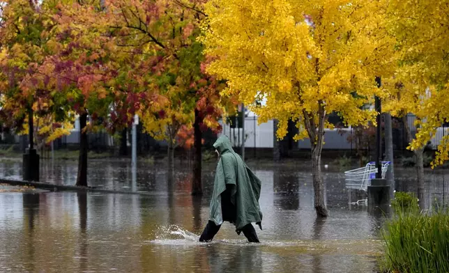 A pedestrian walks along a flooded street during a storm Thursday, Nov. 21, 2024, in Santa Rosa, Calif. (AP Photo/Jeff Chiu)