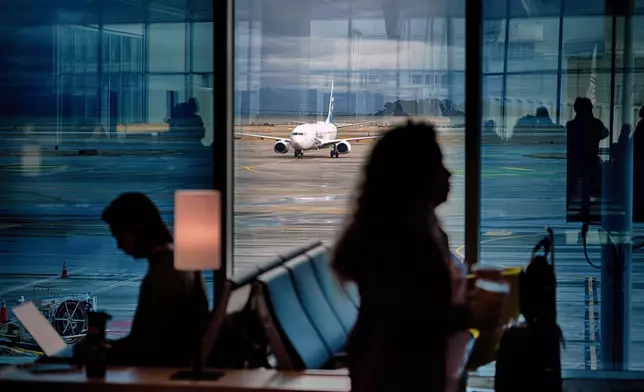 A passenger plane taxies on a water-soaked runway at San Francisco Airport while passengers wait for flights on Thursday, Nov. 21, 2024, in San Francisco. (AP Photo/Andy Bao)