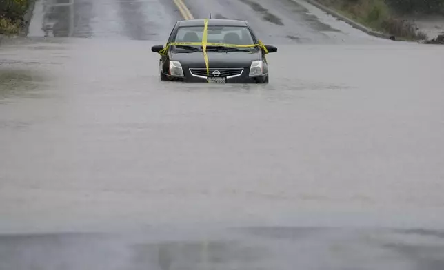 A car is left stranded on a flooded road during a storm Thursday, Nov. 21, 2024, in Windsor, Calif. (AP Photo/Godofredo A. Vásquez)