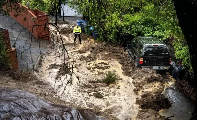 Permit Sonoma Director Tennis Wick crosses a mudslide to inspect a home as heavy rains fall near Healdsburg in unincorporated Sonoma County, Calif., on Friday, Nov. 22, 2024. (AP Photo/Noah Berger)