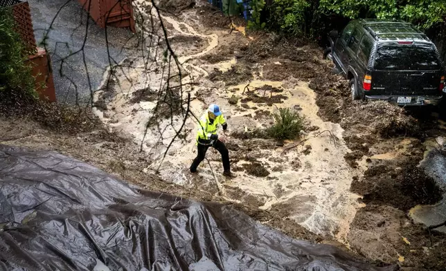 Permit Sonoma Director Tennis Wick crosses a mudslide to inspect a home as heavy rains fall near Healdsburg in unincorporated Sonoma County, Calif., Friday, Nov. 22, 2024. (AP Photo/Noah Berger)