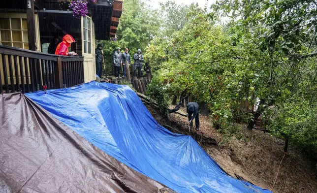 Residents work to shore up a mudslide as heavy rains fall near Healdsburg in unincorporated Sonoma County, Calif., Friday, Nov. 22, 2024. (AP Photo/Noah Berger)