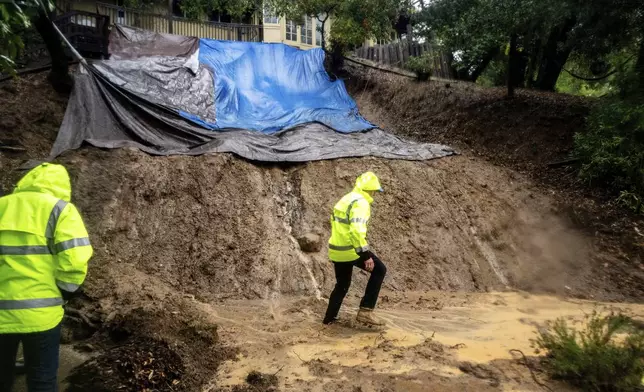 Permit Sonoma Director Tennis Wick crosses a mudslide to inspect a home as heavy rains fall near Healdsburg in unincorporated Sonoma County, Calif., Friday, Nov. 22, 2024. (AP Photo/Noah Berger)