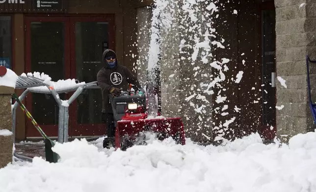 A worker clears the entrance to a building with a snow blower during a storm, Thursday, Nov. 21, 2024, at Sugar Bowl Ski Resort in Norden, Calif. (AP Photo/Brooke Hess-Homeier)