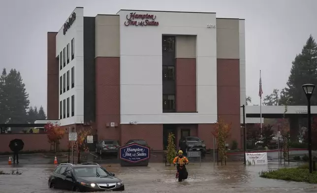 A member of an emergency crew walks in knee-deep flooded street during a storm Thursday, Nov. 21, 2024, in Santa Rosa, Calif. (AP Photo/Jeff Chiu)