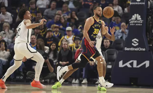 Golden State Warriors guard Stephen Curry (30) passes the ball against Brooklyn Nets forward Jalen Wilson, left, during the first half of an NBA basketball game in San Francisco, Monday, Nov. 25, 2024. (AP Photo/Jed Jacobsohn)