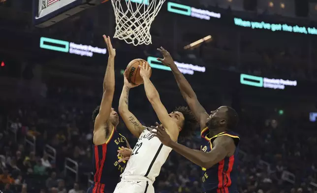 Brooklyn Nets forward Jalen Wilson, center, looks to shoot against Golden State Warriors forwards Draymond Green, right, and Trayce Jackson-Davis, left, during the first half of an NBA basketball game in San Francisco, Monday, Nov. 25, 2024. (AP Photo/Jed Jacobsohn)