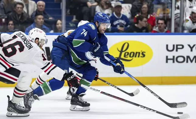 Vancouver Canucks' Jake DeBrusk (74) and Chicago Blackhawks' Jason Dickinson (16) vie for the puck during third period NHL hockey action in Vancouver, B.C., Saturday, Nov. 16, 2024. (Ethan Cairns/The Canadian Press via AP)