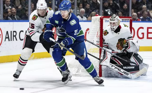 Vancouver Canucks' Danton Heinen (20) and Chicago Blackhawks' Craig Smith (15) vie for the puck as Chicago goaltender Arvid Soderblom (40) watches during third period NHL hockey action in Vancouver, B.C., Saturday, Nov. 16, 2024. (Ethan Cairns/The Canadian Press via AP)