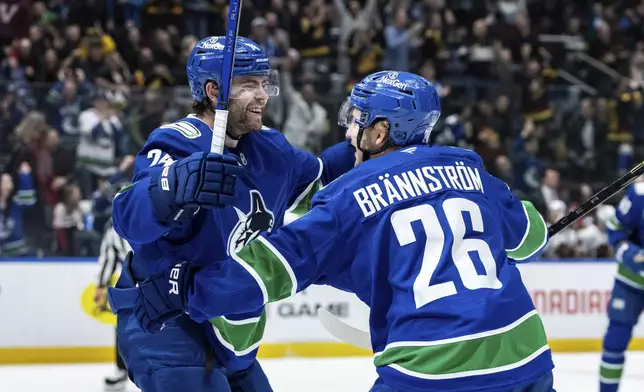 Vancouver Canucks' Erik Brannstrom (26) celebrates his goal against the Chicago Blackhawks with Jake DeBrusk (74) during third period NHL hockey action in Vancouver, B.C., Saturday, Nov. 16, 2024. (Ethan Cairns/The Canadian Press via AP)