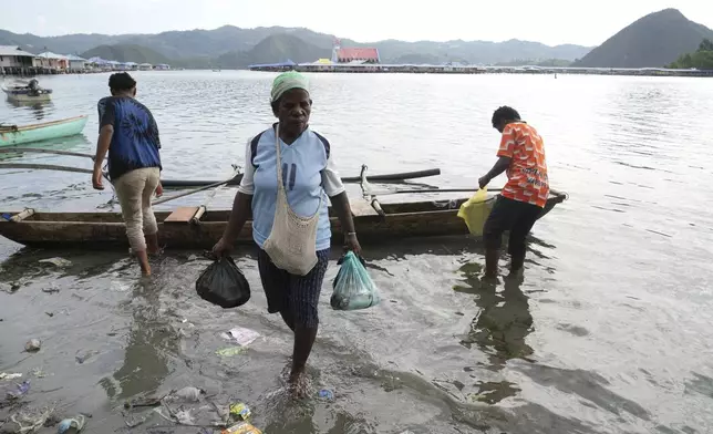 A woman carries fish in plastic bags to a market at Enggros village in Jayapura, Papua province, Indonesia on Wednesday, Oct. 2, 2024. (AP Photo/Firdia Lisnawati)