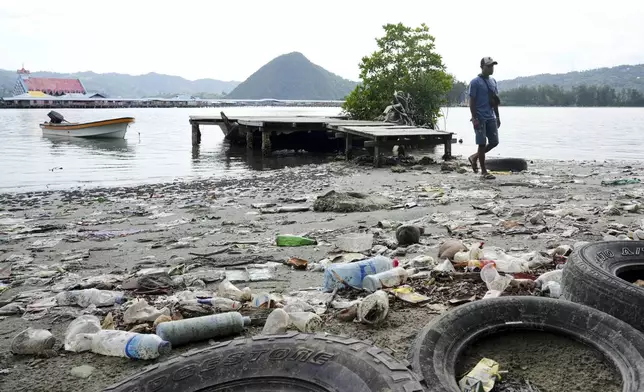 A man walks past plastic waste strewn along at Enggros village beach in Jayapura, Papua province, Indonesia on Wednesday, Oct. 2, 2024. (AP Photo/Firdia Lisnawati)