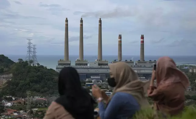 FILE - Women sit on a hill overlooking the Suralaya coal power plant in Cilegon, Indonesia, Jan. 8, 2023. (AP Photo/Dita Alangkara, File)