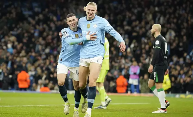 Manchester City's Erling Haaland, center, celebrates with Phil Foden, left, after scoring his side's third goal during the Champions League opening phase soccer match between Manchester City and Feyenoord at the Etihad Stadium in Manchester, England, Tuesday, Nov. 26, 2024. (AP Photo/Dave Thompson)