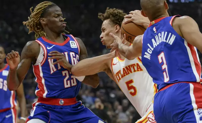 Atlanta Hawks guard Dyson Daniels (5) drives to the basket between Sacramento Kings guard Keon Ellis (23) and Jordan McLaughlin during the first half of an NBA basketball game in Sacramento, Calif., Monday, Nov. 18, 2024. (AP Photo/Randall Benton)