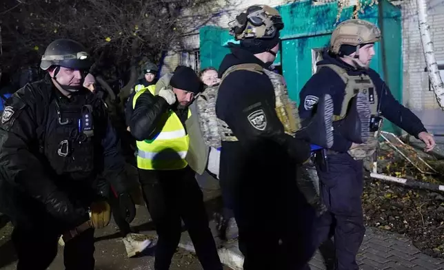 In this photo provided by the Ukrainian Emergency Service, police officers evacuate an injured resident following a Russian rocket attack that hit a multi-storey apartment building in Sumy, Ukraine, Sunday, Nov. 17, 2024. (Ukrainian Emergency Service via AP)