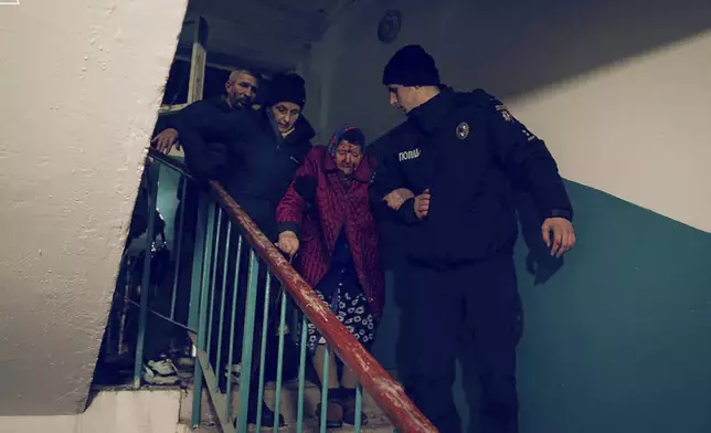 In this photo provided by the Ukrainian Emergency Service, a police officer, right, evacuates an elderly resident following a Russian rocket attack that hit a multi-storey apartment building in Sumy, Ukraine, Sunday, Nov. 17, 2024. (Ukrainian Emergency Service via AP)