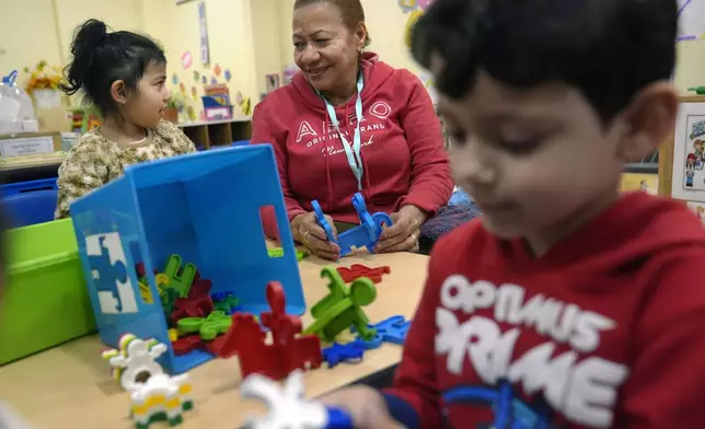 Volunteer Evangelista Baez, 72, of Providence, R.I., center, supervises three-year-olds Scarlett Mendoza, left, and Gabriel Kubbe, right, in an early childcare program at Federal Hill House, Tuesday, Nov. 12, 2024, in Providence, R.I. (AP Photo/Steven Senne)