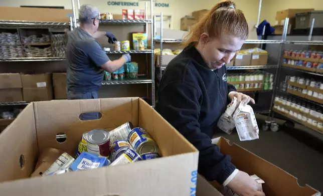 Volunteer Madison Turner, of Providence, R.I. right, organizes food items in a food pantry at Federal Hill House, Tuesday, Nov. 12, 2024, in Providence, R.I. (AP Photo/Steven Senne)