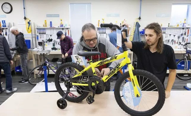 Volunteer and board member Kurt Glathar, left, works on a children's bicycle alongside fellow volunteer Simon Zacher at Lincoln Bike Kitchen on Tuesday, Nov. 12, 2024, in Lincoln, Neb. (AP Photo/Rebecca S. Gratz)