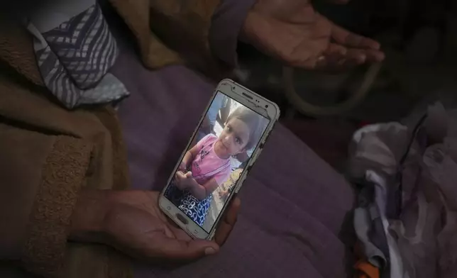 Areej al Qadi shows shows a picture of her daughter Laila at her tent in a refugee camp in Khan Younis, Gaza Strip, Thursday Nov. 21, 2024. Seven-year-old Hamza, his five-year-old brother Abdelaziz, and his four-year-old sister Laila Hassan were among 9 people killed by an Israeli strike in Khan Younis on Wednesday. Palestinian health officials say the death toll in the Gaza Strip from the 13-month-old war between Israel and Hamas has surpassed 44,000. (AP Photo/Abdel Kareem Hana)