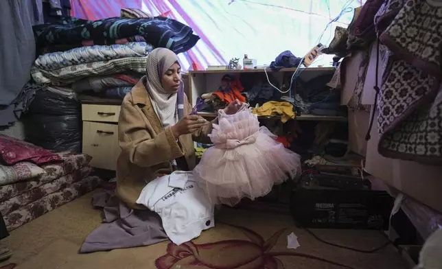 Areej al Qadi shows dress of her daughter Laila at her tent in a refugee camp in Khan Younis, Gaza Strip, Thursday Nov. 21, 2024. Seven-year-old Hamza, his five-year-old brother Abdelaziz, and his four-year-old sister Laila Hassan were among 9 people killed by an Israeli strike in Khan Younis on Wednesday. Palestinian health officials say the death toll in the Gaza Strip from the 13-month-old war between Israel and Hamas has surpassed 44,000. (AP Photo/Abdel Kareem Hana)