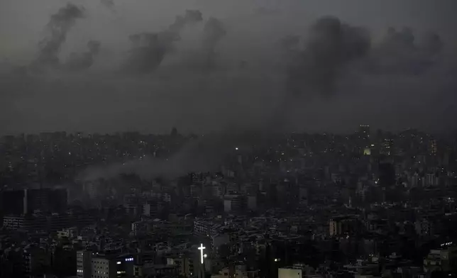 The cross atop of Our Lady of Hadath Church lights up as smoke rises after an Israeli airstrike on Dahiyeh, in the southern suburb of Beirut, Lebanon, Thursday, Nov. 21, 2024. (AP Photo/Bilal Hussein)