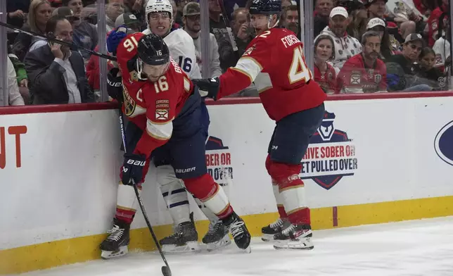 Florida Panthers center Aleksander Barkov (16) controls the puck against Toronto Maple Leafs right wing Mitch Marner, center, during the first period of an NHL hockey game, Wednesday, Nov. 27, 2024, in Sunrise, Fla. (AP Photo/Lynne Sladky)