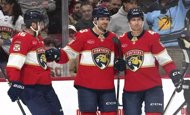 Florida Panthers center Sam Reinhart, center, celebrates with center Aleksander Barkov (16) and defenseman Gustav Forsling, right, after scoring a goal during the second period of an NHL hockey game against the Toronto Maple Leafs, Wednesday, Nov. 27, 2024, in Sunrise, Fla. (AP Photo/Lynne Sladky)