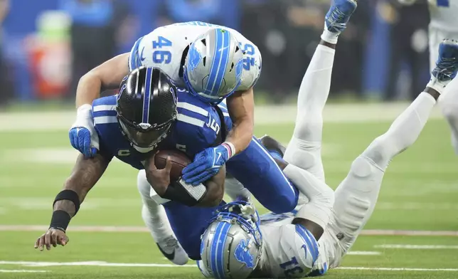 Indianapolis Colts quarterback Anthony Richardson (5) is tackled by Detroit Lions safety Kerby Joseph (31) and linebacker Jack Campbell (46) during the first half of an NFL football game, Sunday, Nov. 24, 2024, in Indianapolis. (AP Photo/AJ Mast)