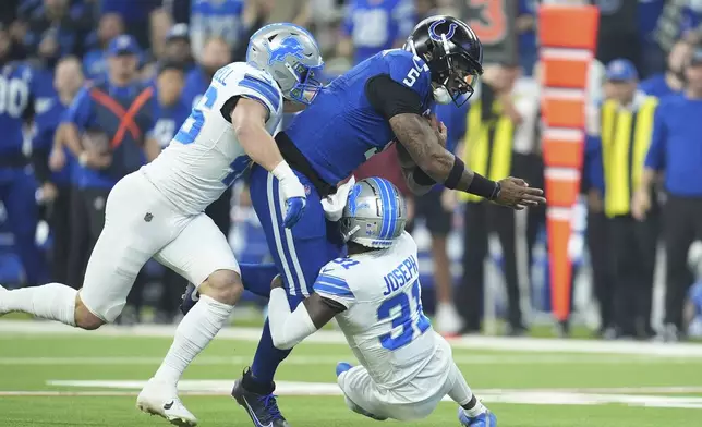 Indianapolis Colts quarterback Anthony Richardson (5) is tackled by Detroit Lions linebacker Jack Campbell, left, and safety Kerby Joseph (31) during the first half of an NFL football game, Sunday, Nov. 24, 2024, in Indianapolis. (AP Photo/Michael Conroy)