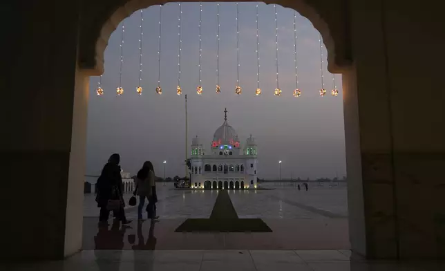 Sikh pilgrims arrive at the shrine of first Sikh guru, Guru Nanak Dev, which is illuminated for the birth anniversary celebrations at the Gurdwara Darbar Sahib in Kartarpur, Pakistan, Monday, Nov. 18, 2024. (AP Photo/Anjum Naveed)