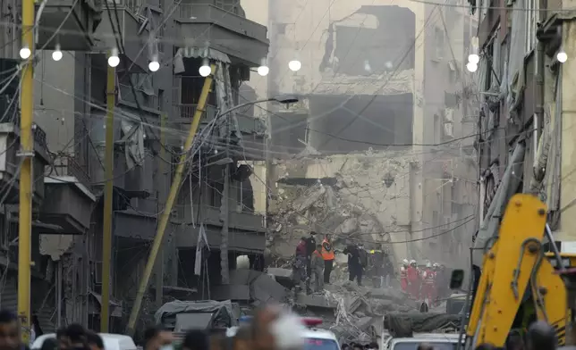 Rescue workers and people gather at the site of an Israeli airstrike that hit central Beirut, Lebanon, Saturday, Nov. 23, 2024. (AP Photo/Hassan Ammar)