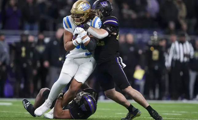 UCLA tight end Moliki Matavao is tackled by Washington linebacker Alphonzo Tuputala (11) and linebacker Carson Bruener, right, during the first half of an NCAA college football game Friday, Nov. 15, 2024, in Seattle. (AP Photo/Lindsey Wasson)