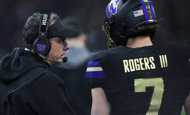 Washington head coach Jedd Fisch talks with quarterback Will Rogers during the first half of an NCAA college football game against UCLA, Friday, Nov. 15, 2024, in Seattle. (AP Photo/Lindsey Wasson)