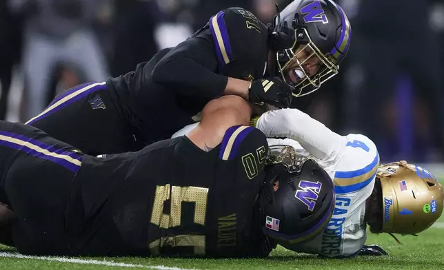 Washington edge Isaiah Ward, top, and defensive tackle Sebastian Valdez (50) sack UCLA quarterback Ethan Garbers (4) during the first half of an NCAA college football game Friday, Nov. 15, 2024, in Seattle. (AP Photo/Lindsey Wasson)