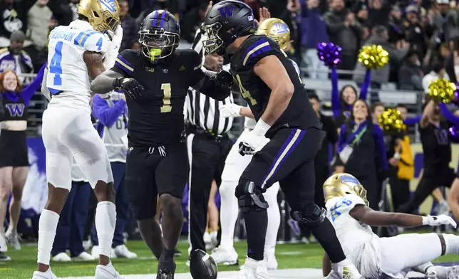 Washington running back Jonah Coleman (1) celebrates his touchdown with offensive lineman Drew Azzopardi (74) as UCLA defensive back Bryan Addison (4) looks away during the first half of an NCAA college football game Friday, Nov. 15, 2024, in Seattle. (AP Photo/Lindsey Wasson)