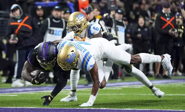 Washington running back Jonah Coleman scores a touchdown against UCLA defensive back Jaylin Davies (6) and defensive back Bryan Addison (4) during the first half of an NCAA college football game Friday, Nov. 15, 2024, in Seattle. (AP Photo/Lindsey Wasson)