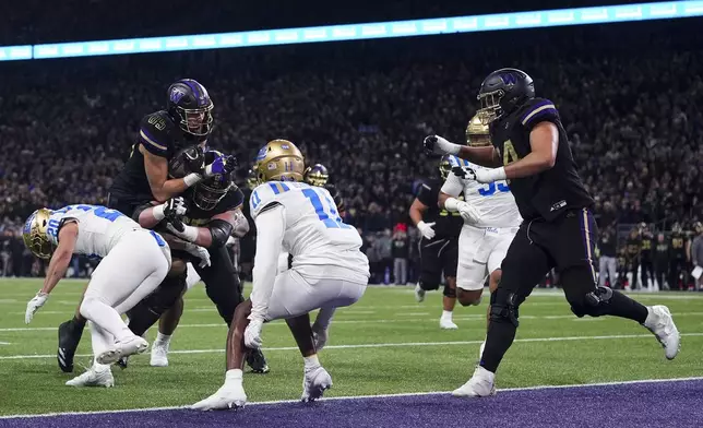 Washington tight end Keleki Latu (85) runs for a touchdown against UCLA linebacker Kain Medrano (20) and defensive back Ramon Henderson (11) during the first half of an NCAA college football game Friday, Nov. 15, 2024, in Seattle. (AP Photo/Lindsey Wasson)