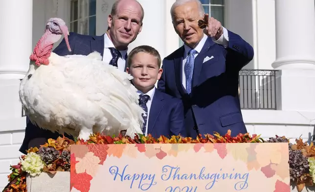 President Joe Biden, right, stands with John Zimmerman, left, chair of the National Turkey Federation, his son Grant Zimmerman, center, and the national Thanksgiving turkey, Peach, during a pardoning ceremony on the South Lawn of the White House in Washington, Monday, Nov. 25, 2024. (AP Photo/Susan Walsh)