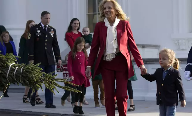 First lady Jill Biden, second right, walks with her grandson Beau Biden, right, to receive the official 2024 White House Christmas Tree on the North Portico of the White House in Washington, Monday, Nov. 25, 2024. Cartner's Christmas Tree Farm from Newland, N.C., provided the Fraser fir that will be displayed in the Blue Room of the White House. (AP Photo/Susan Walsh)