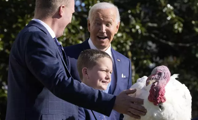 President Joe Biden is pictured with John Zimmerman, chair of the National Turkey Federation, from left, and Zimmerman's son Grant, after pardoning the national Thanksgiving turkey Peach during a ceremony on the South Lawn of the White House in Washington, Monday, Nov. 25, 2024. (AP Photo/Mark Schiefelbein)